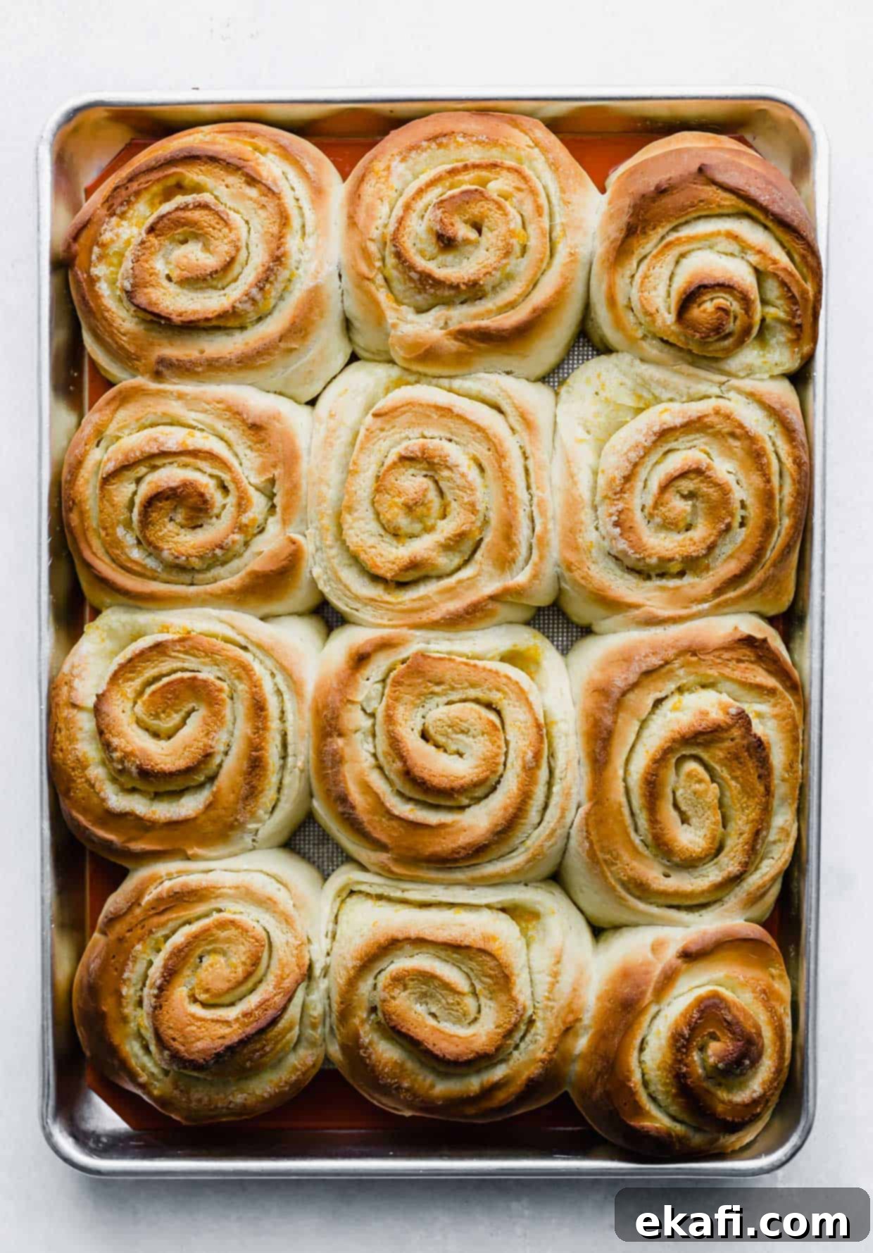 Orange Rolls 10 Freshly baked golden-brown Orange Rolls on a baking sheet, before frosting, showing their beautiful rise and texture.