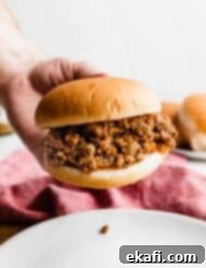 Hearty Old School Sloppy Joes 7 A hand holding up a hamburger bun that is very full of the best homemade sloppy Joe mix.