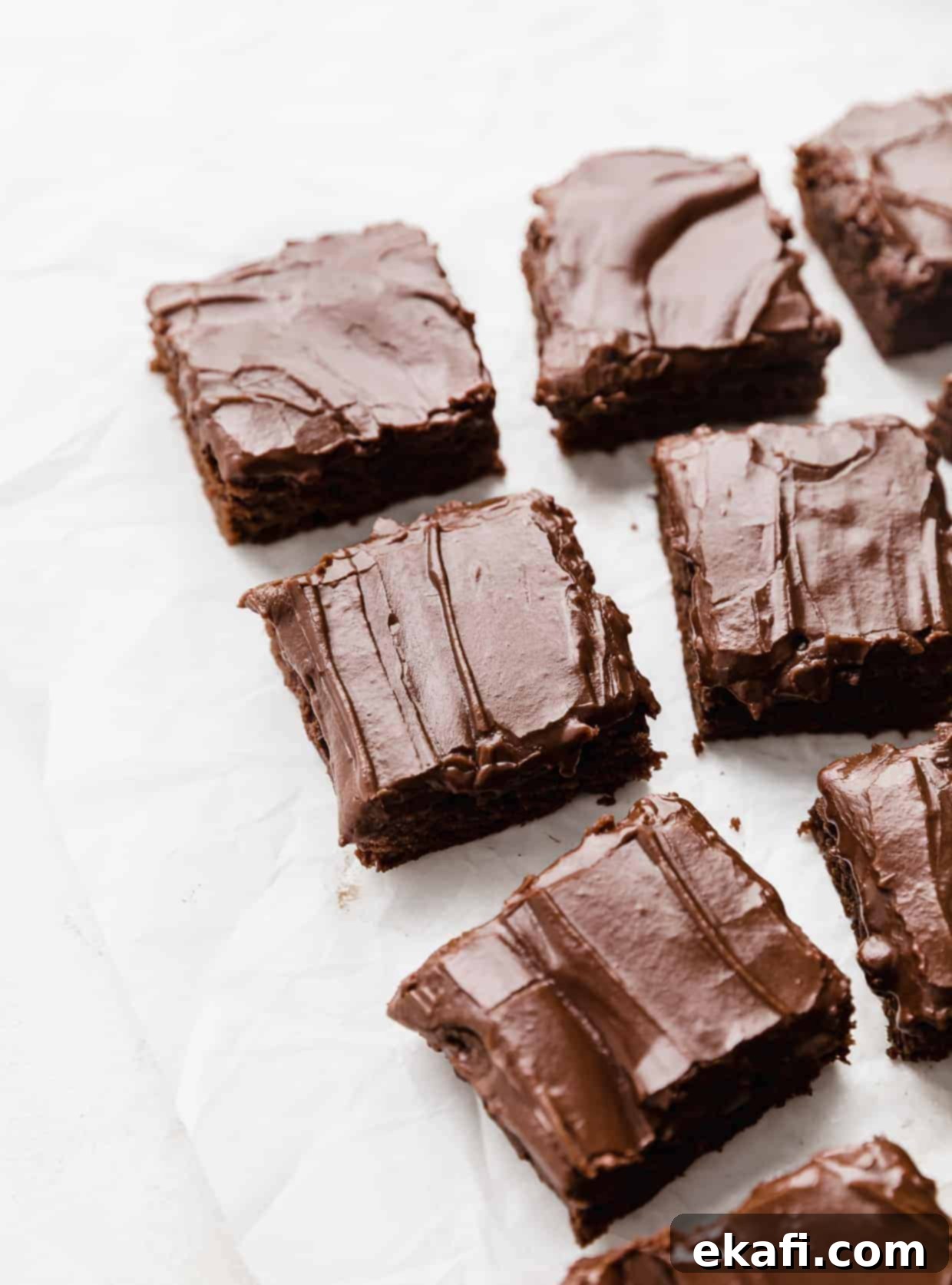 School Cafeteria Brownies 12 Close-up of decadent chocolate frosted lunch lady brownies, neatly cut into squares and artfully arranged on a pristine white background.