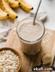 Σμούθι Γαλουχίας 8 Ένα Smoothie Θηλασμού σε μια μικρή ξύλινη επιφάνεια κοπής με ώριμες μπανάνες στο φόντο.