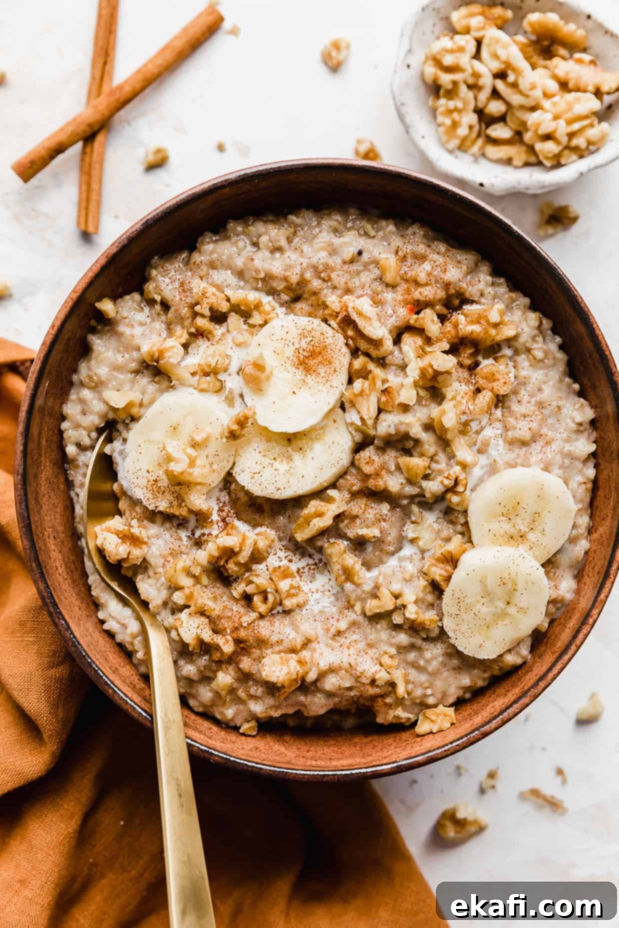Banana Steel Cut Oat Delight 2 A brown bowl full of Banana Steel Cut Oats garnished with sliced bananas and nuts, ready to be enjoyed as a healthy and flavorful breakfast.