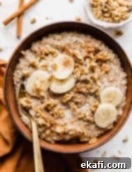 Banana Steel Cut Oat Delight 11 A brown bowl full of Banana Steel Cut Oats garnished with sliced bananas and nuts.