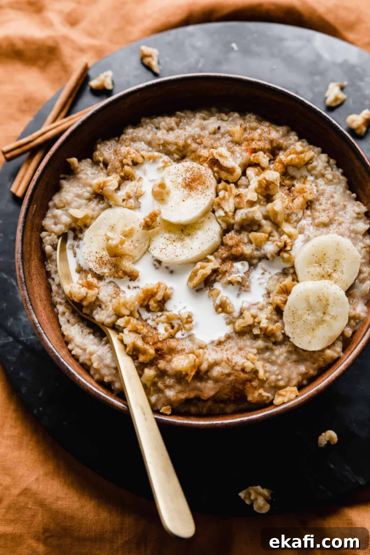 Banana Steel Cut Oat Delight 9 A wooden bowl full of Banana Steel Cut Oats topped with sliced bananas and walnuts against a black background, emphasizing its gourmet appeal.