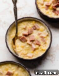 Hearty Ham and Sweet Corn Chowder 13 A close up of Ham and Corn Chowder in a black bowl against a white textured background.