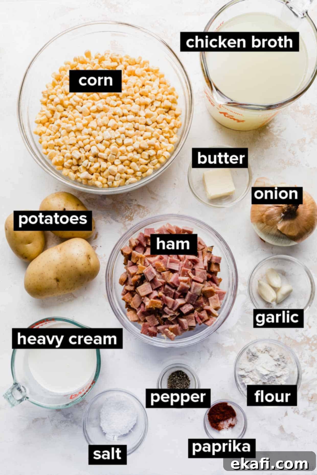 Hearty Ham and Sweet Corn Chowder 3 Ingredients used to make ham and corn chowder laid out on a white background, including ham, corn, potatoes, onion, and cream.