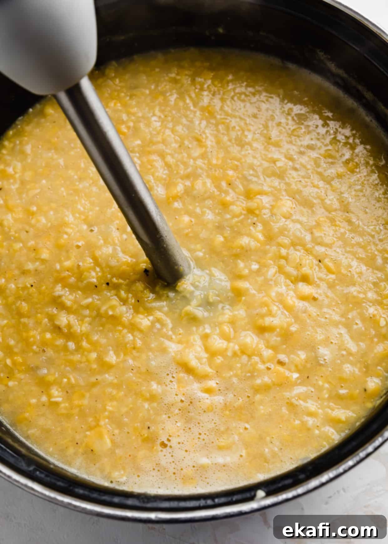 Hearty Ham and Sweet Corn Chowder 9 An immersion blender in a large pot full of cooked corn and potatoes for making Ham and Corn Chowder to achieve creamy texture.