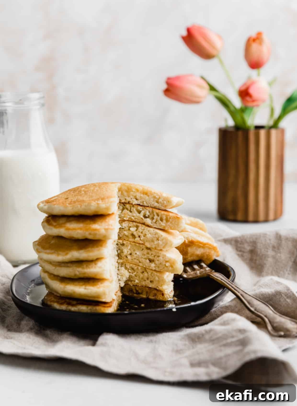 Fluffy Almond Milk Pancakes 12 Fluffy Almond Milk Pancakes on a black plate with a wedge of pancake cut out of the stack.