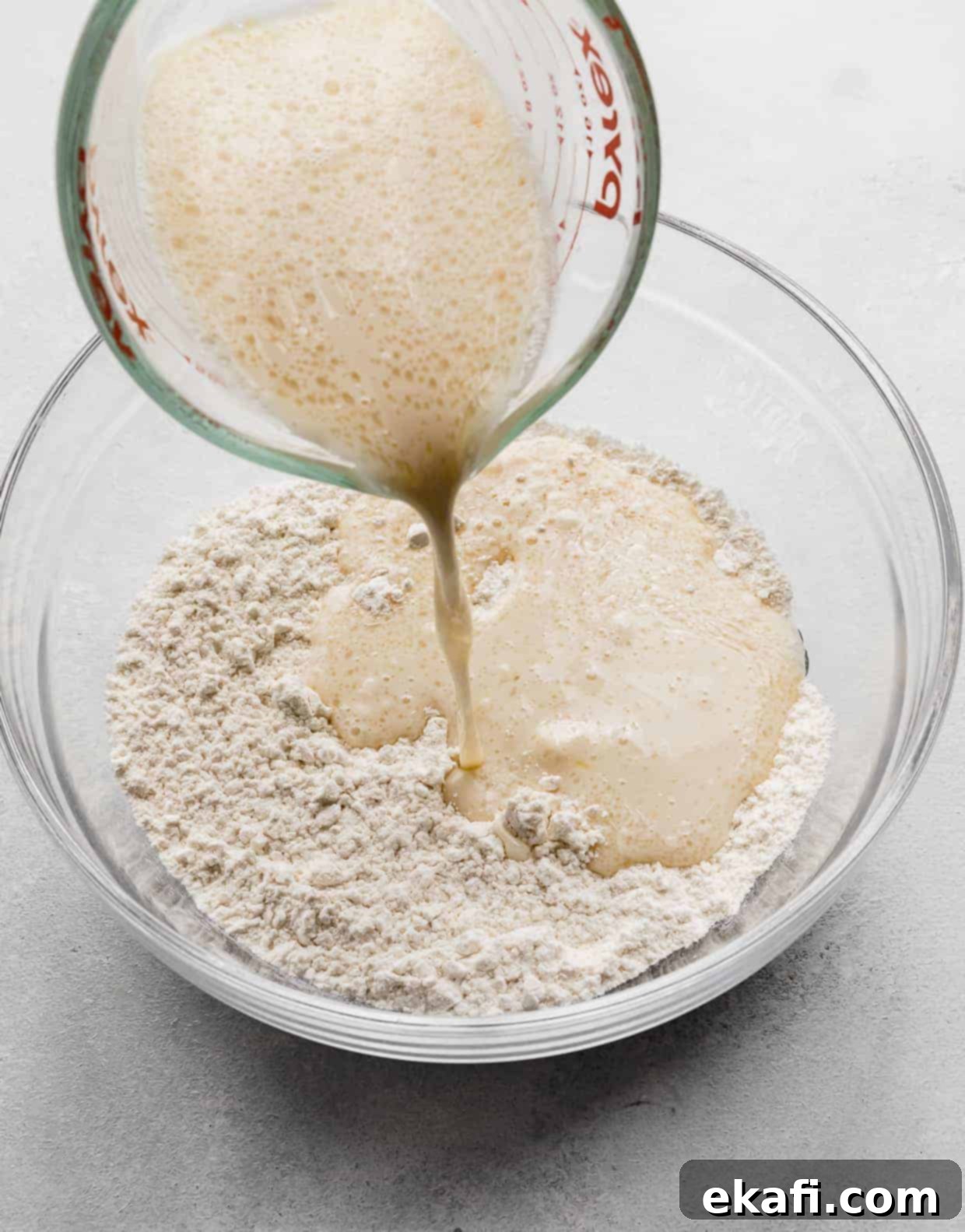 Fluffy Almond Milk Pancakes 6 Wet ingredients being poured into a glass bowl full of flour.