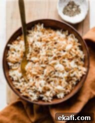 Orzo Pilaf 11 Orzo Rice Pilaf in a brown bowl on a wooden cutting board, ready to serve.