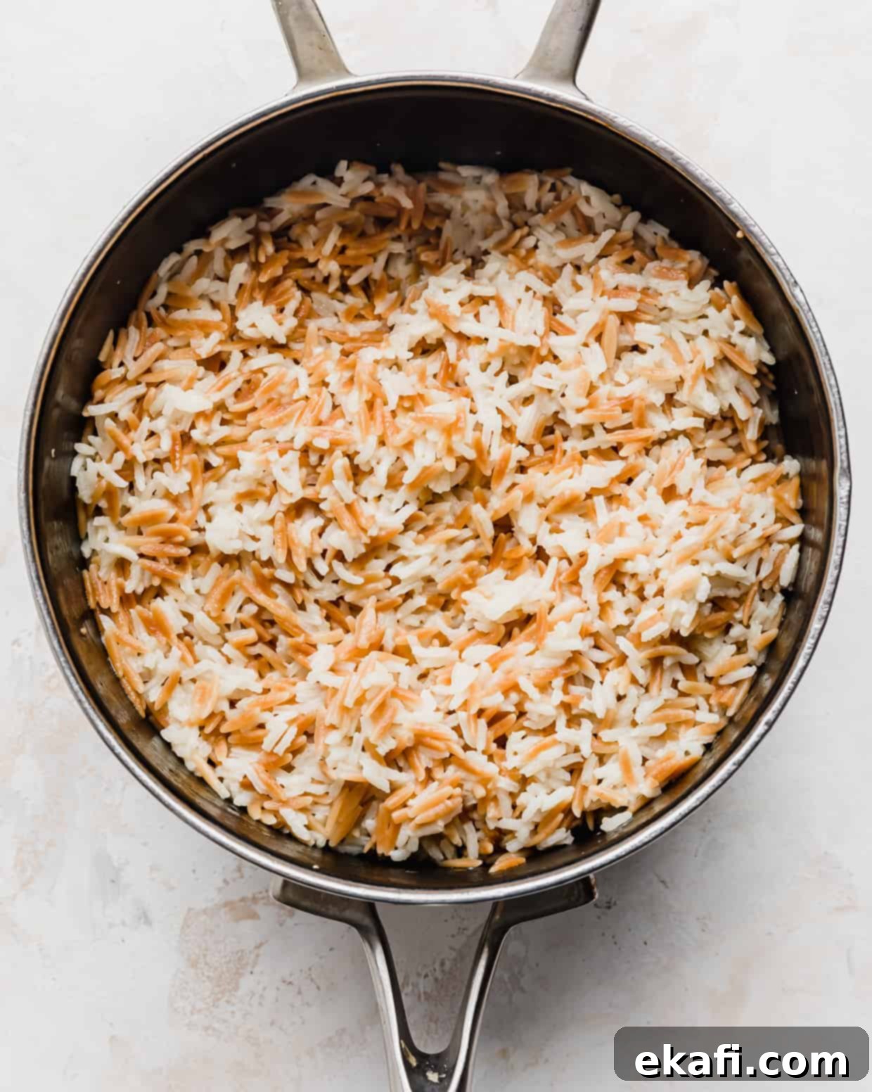 Orzo Pilaf 8 Fluffy, perfectly cooked Orzo Rice Pilaf resting in a saucepan after simmering, steam rising gently.