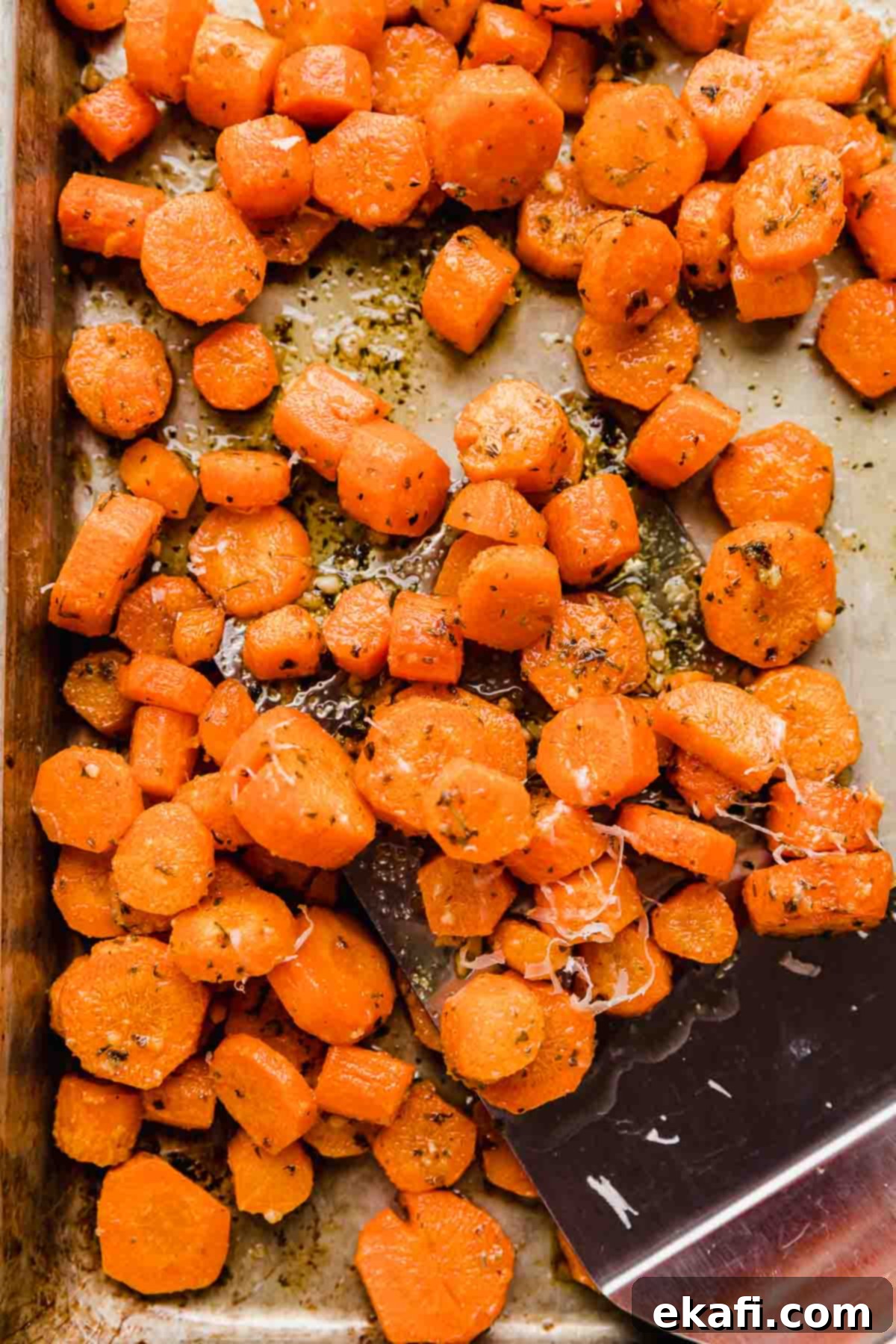 Golden Parmesan Roasted Carrots 2 Perfectly sliced Garlic Butter Roasted Carrots generously coated with parmesan, fresh out of the oven on a baking sheet.