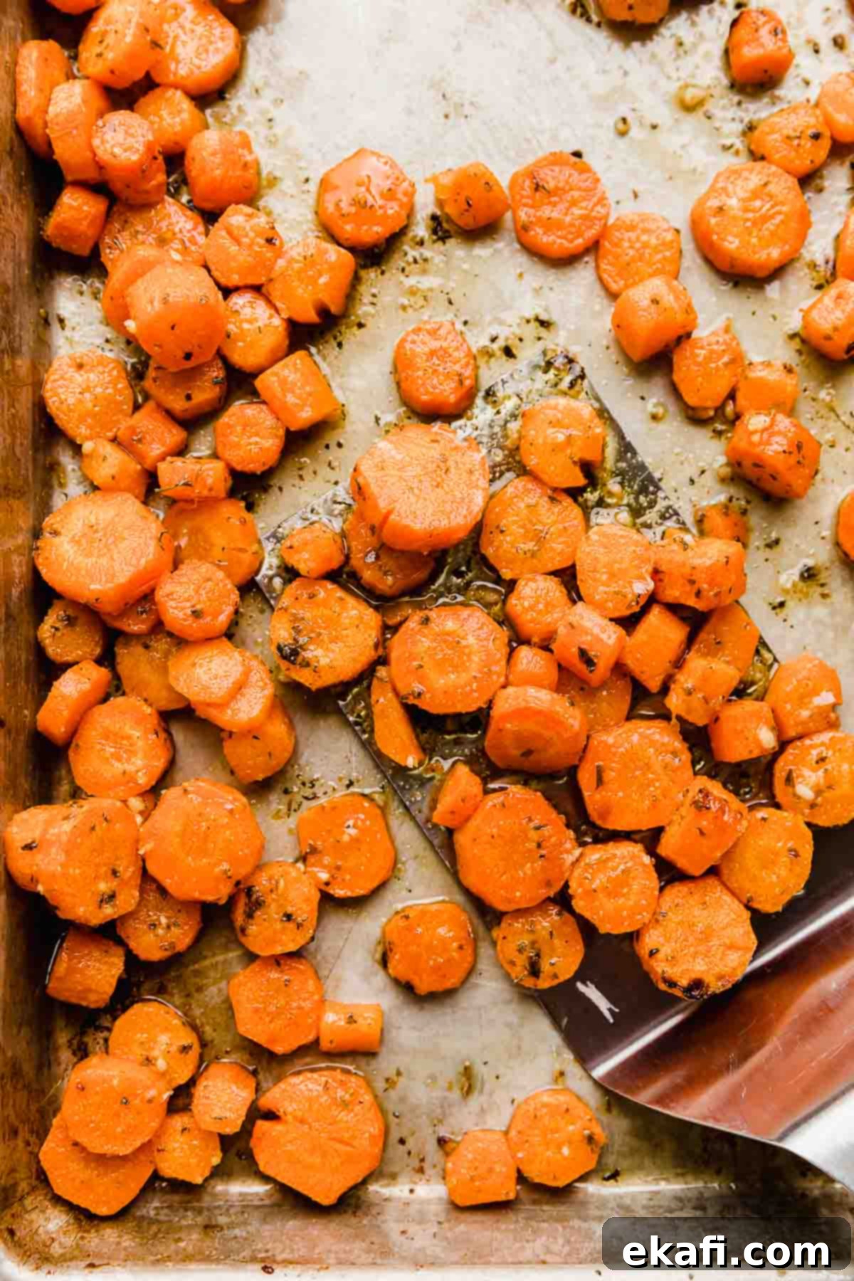 Golden Parmesan Roasted Carrots 5 Close-up of garlic parmesan roasted carrots, perfectly sliced into coins, glistening with butter and cheese on a baking sheet.