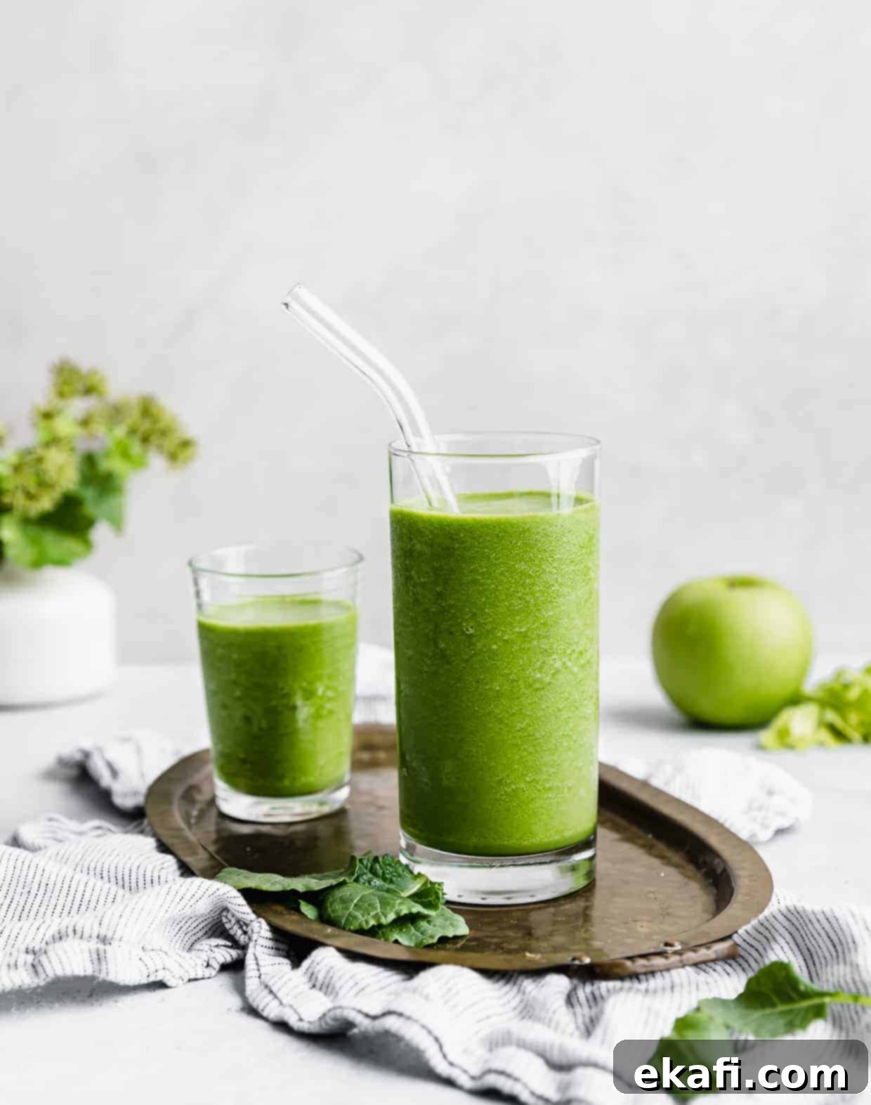 Green Celery Smoothie 2 A clear glass full of bright green celery smoothie with a glass straw in the cup.