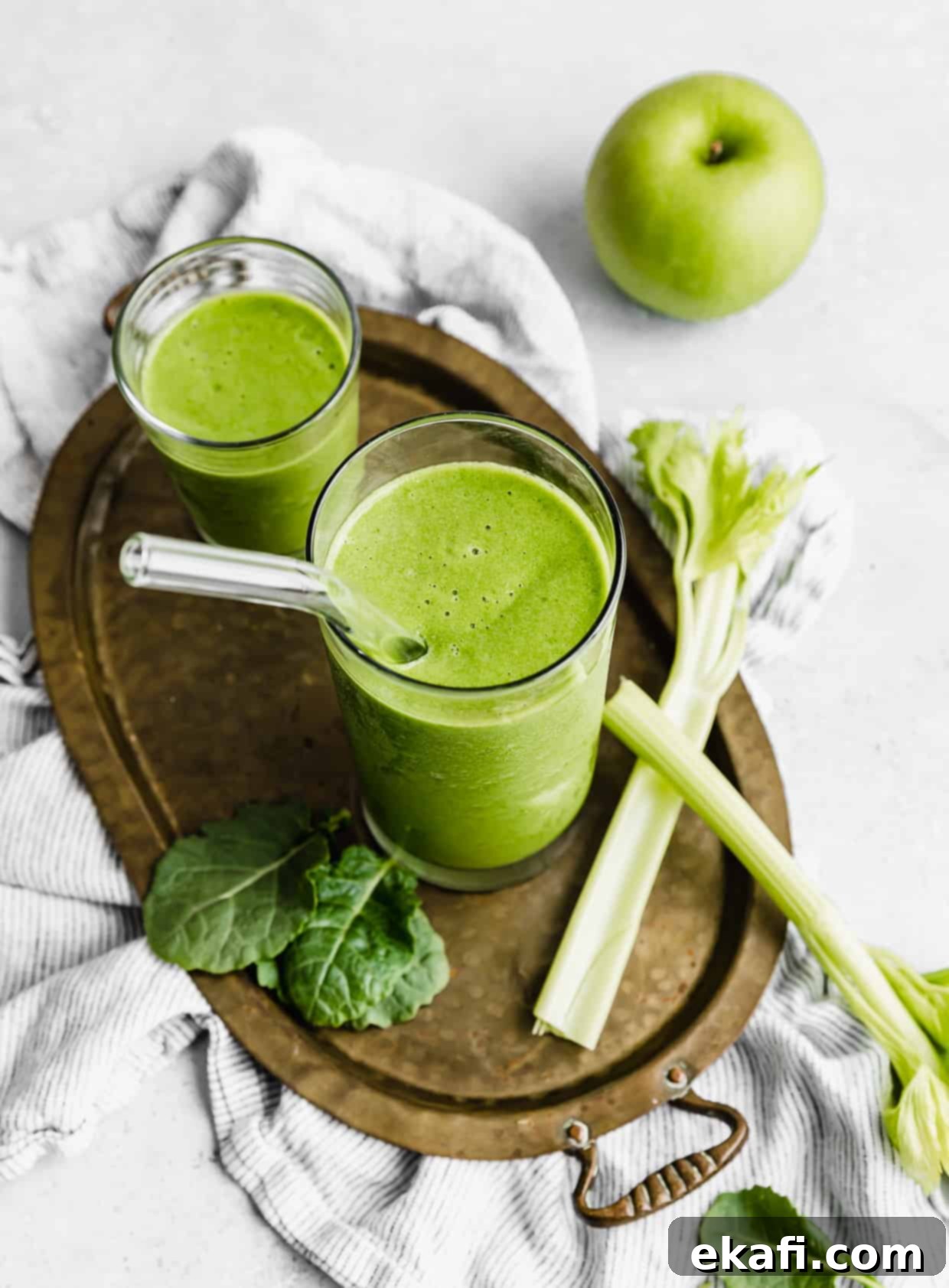 Green Celery Smoothie 7 A celery smoothie in a glass cup with a glass straw in it.