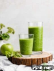 Green Celery Smoothie 9 Two glasses full of dark green celery smoothie on a wooden round board.