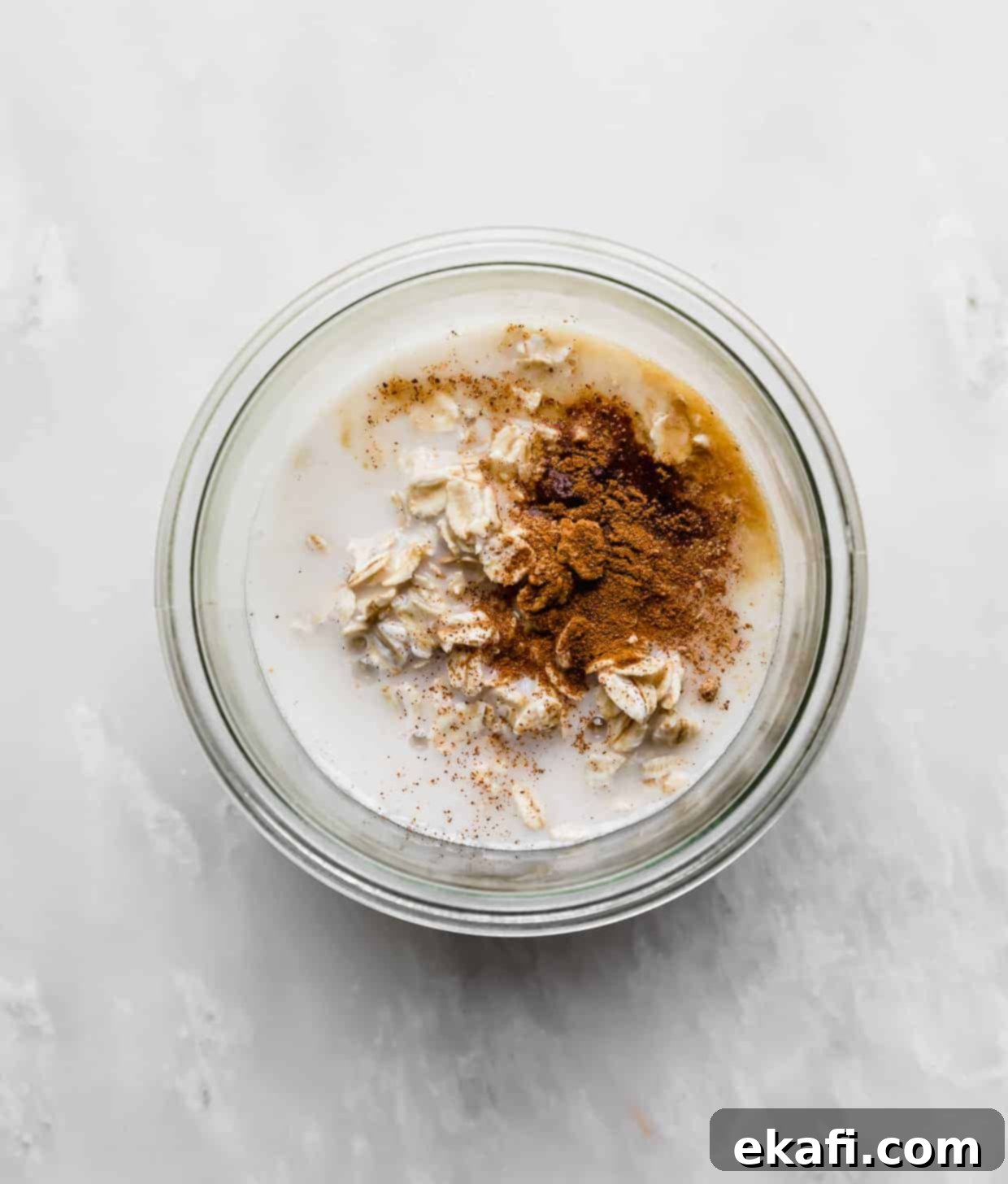 Dreamy Mango Overnight Oats 5 A glass jar full of rolled oats, milk, cinnamon, and nutmeg.