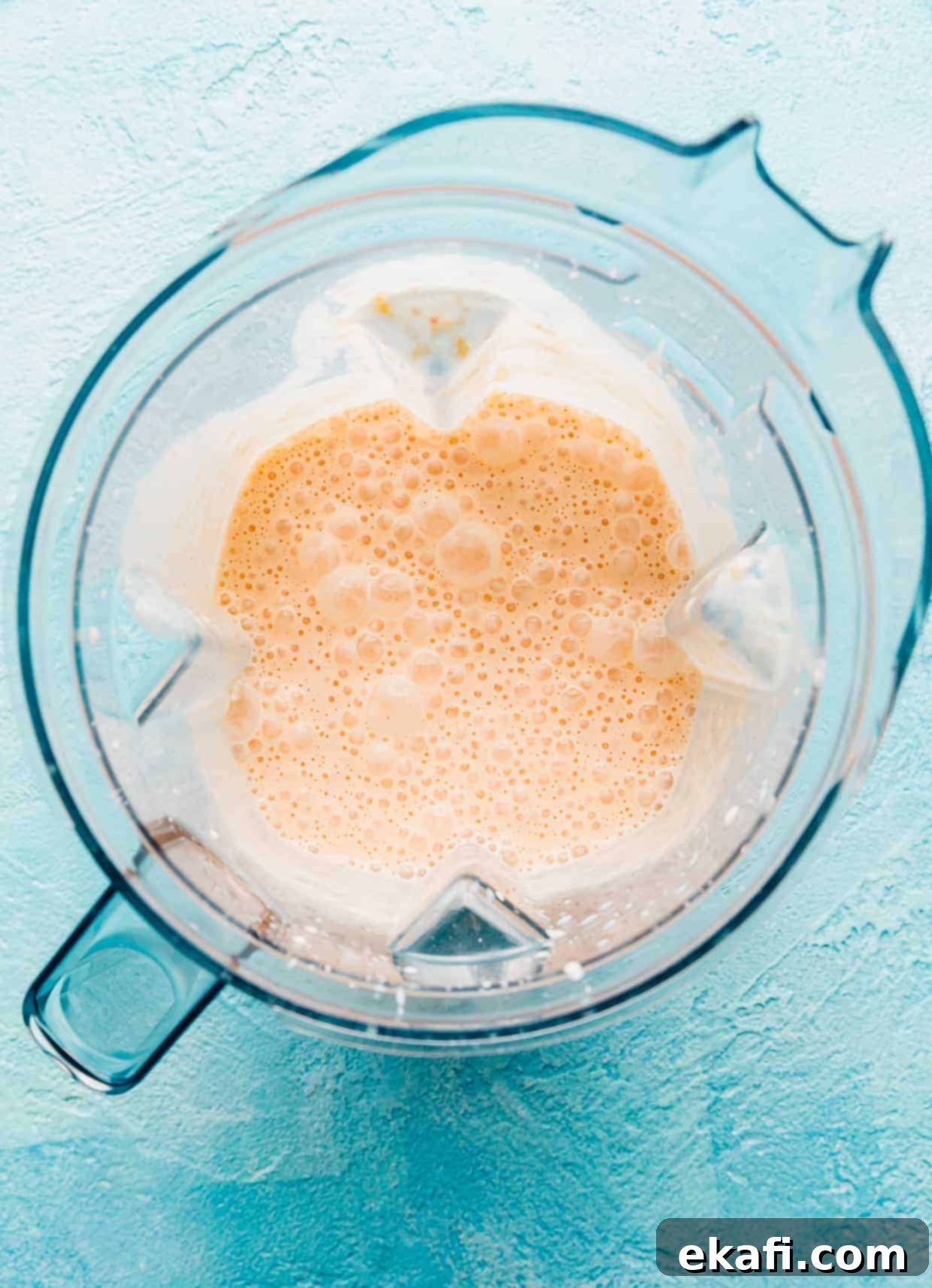 Velvet Peach Shake 5 A blended peach milkshake mixture swirling inside a blender, achieving a smooth and creamy consistency.