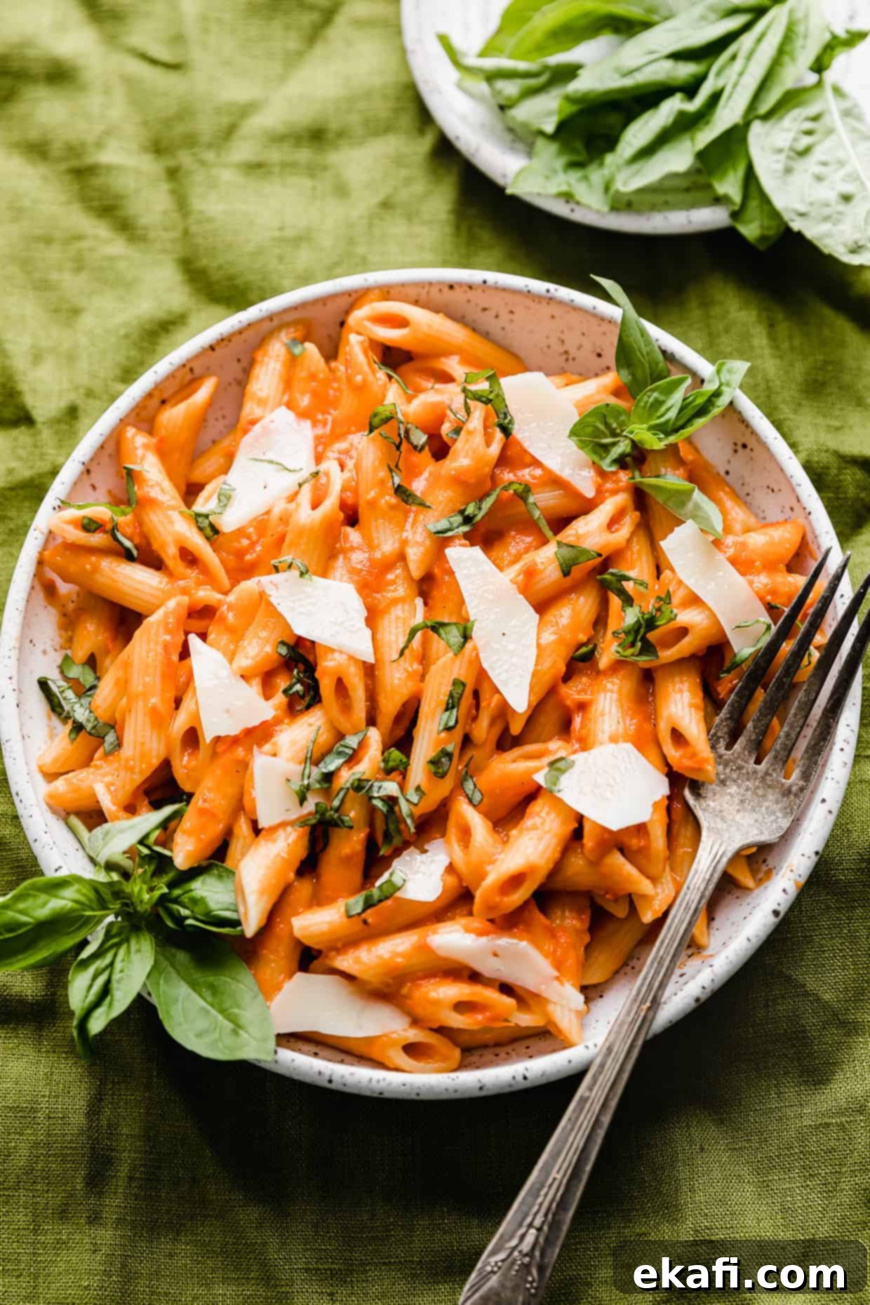 Perfect Penne Pomodoro 2 A white plate full of red Penne Pomodoro pasta topped with fresh basil, ready to be served.