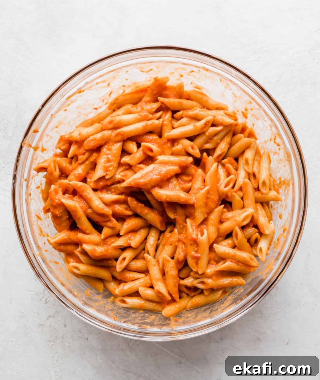 Perfect Penne Pomodoro 7 Cooked penne noodles thoroughly tossed in a rich red sauce in a clear glass bowl, ready for garnishing.