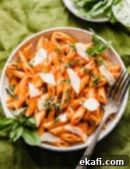 Perfect Penne Pomodoro 9 A white plate full of red Penne Pomodoro pasta topped with fresh basil.