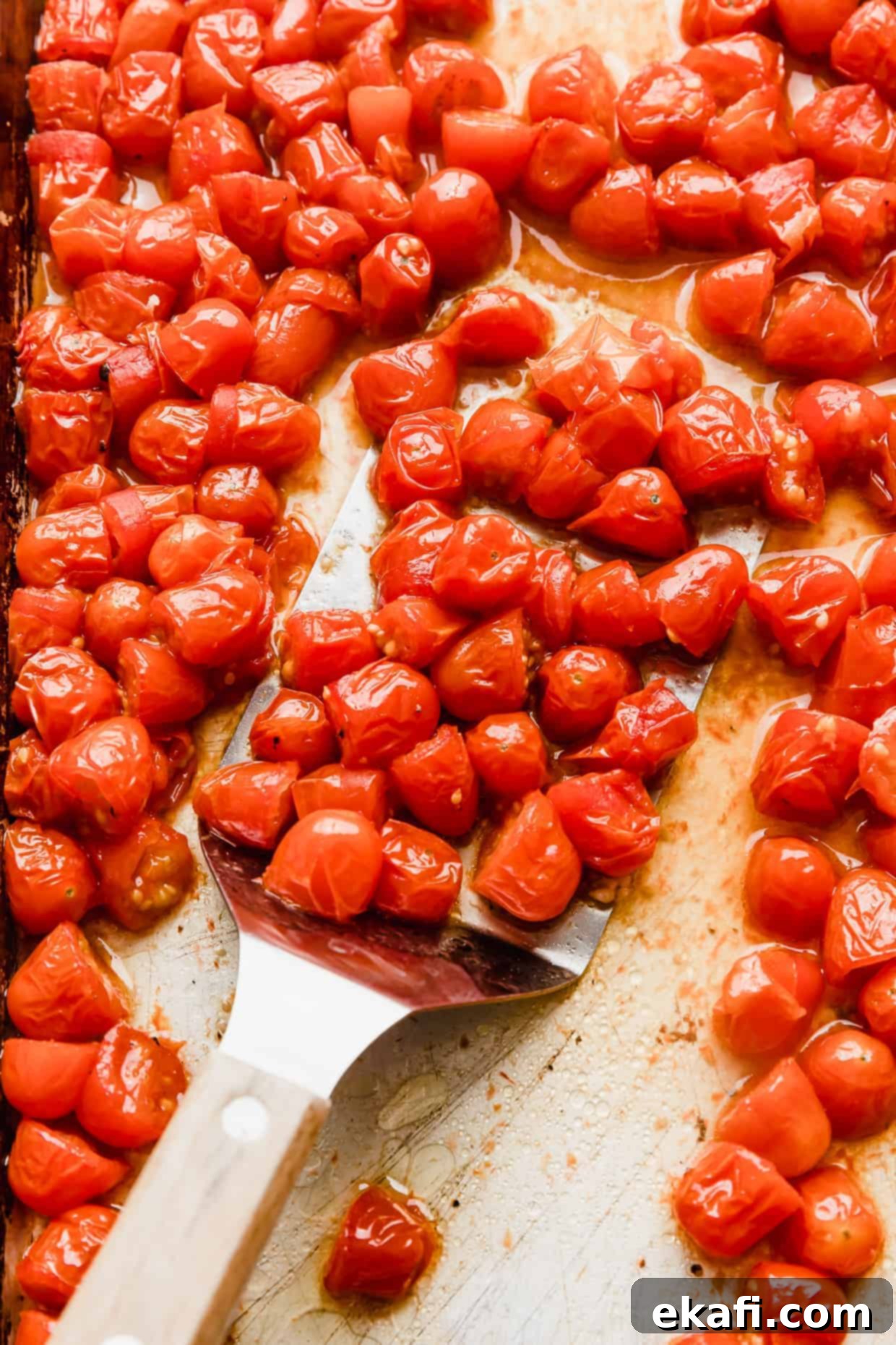 Blistered Grape Tomatoes 2 Roasted grape tomatoes on a baking sheet, golden and slightly shriveled.