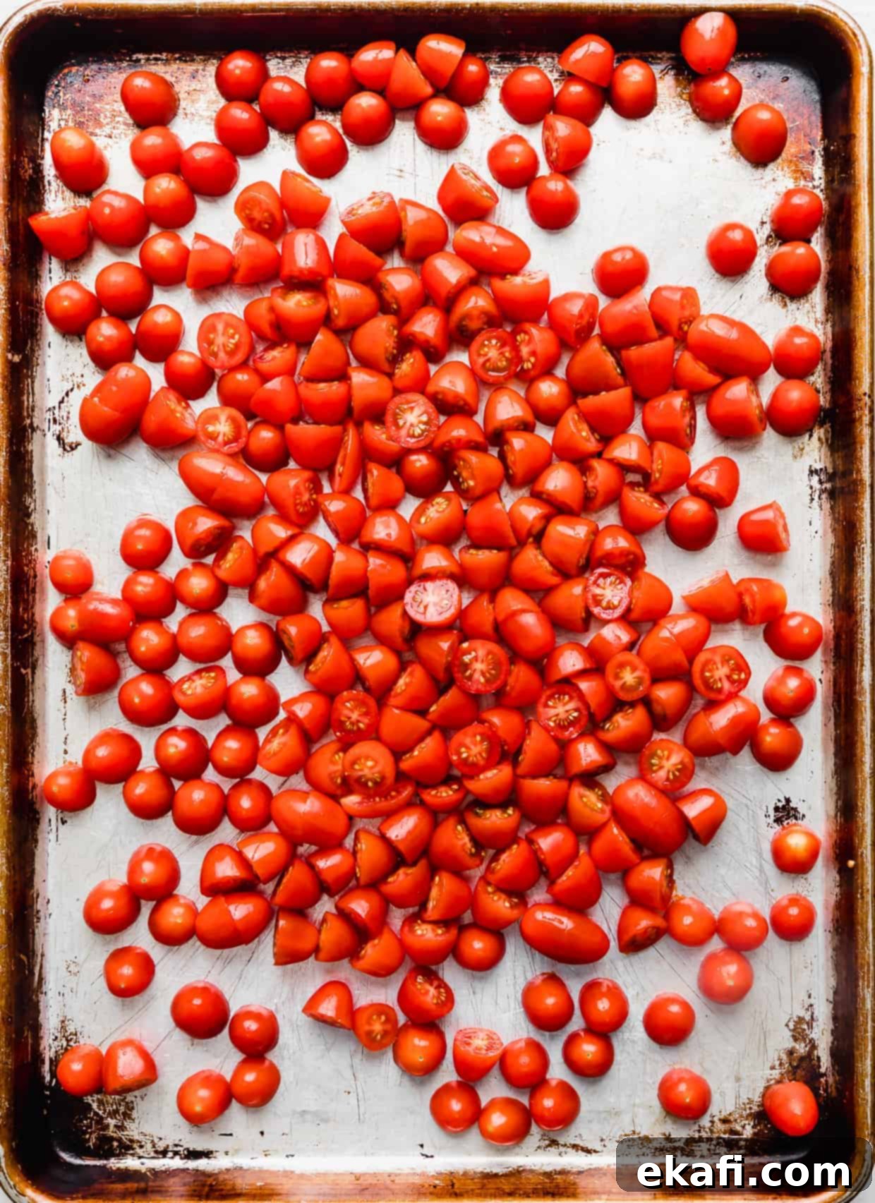 Blistered Grape Tomatoes 4 Fresh grape tomatoes arranged on a baking sheet, glistening with olive oil.