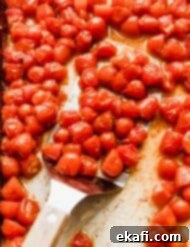 Blistered Grape Tomatoes 10 Roasted grape tomatoes on a baking sheet, golden and slightly shriveled.