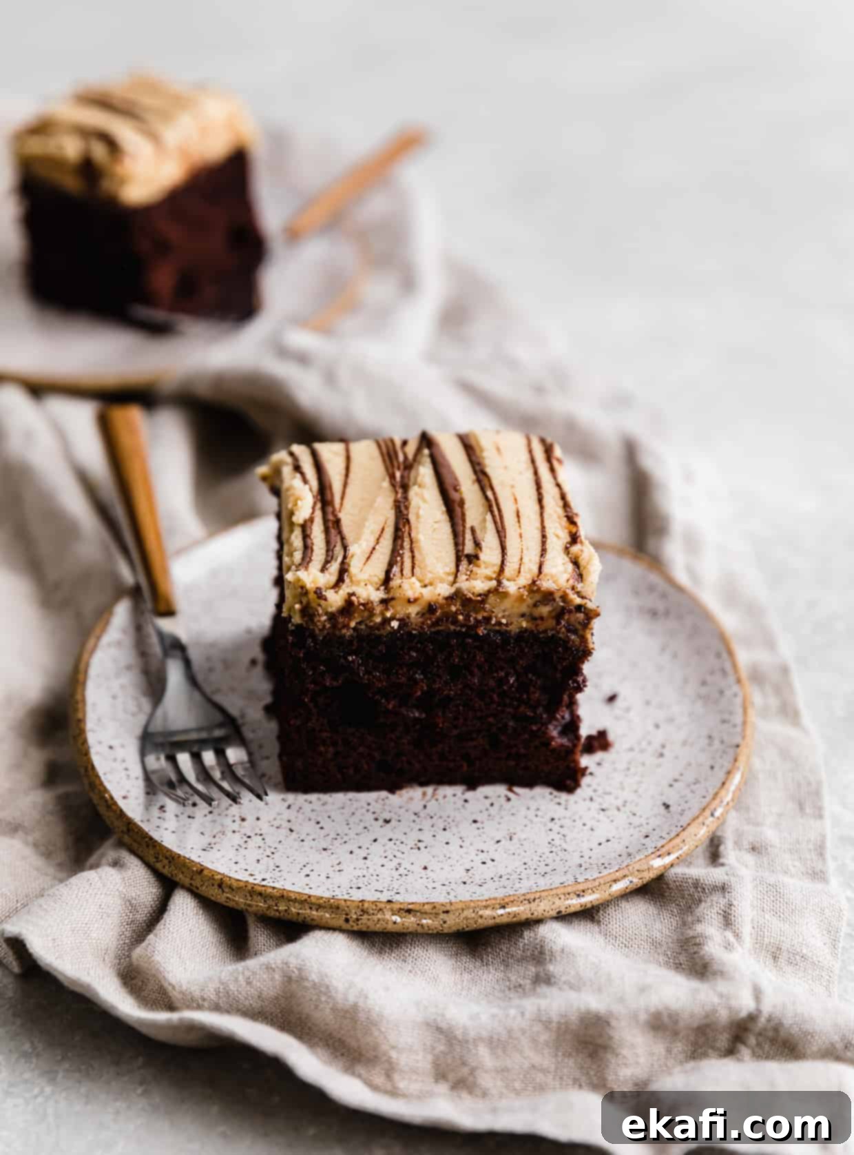 Chocolate Peanut Butter Symphony 13 A perfectly square slice of rich Chocolate Cake with Peanut Butter Frosting resting on a light-colored plate, with a brown fork placed elegantly to the side.