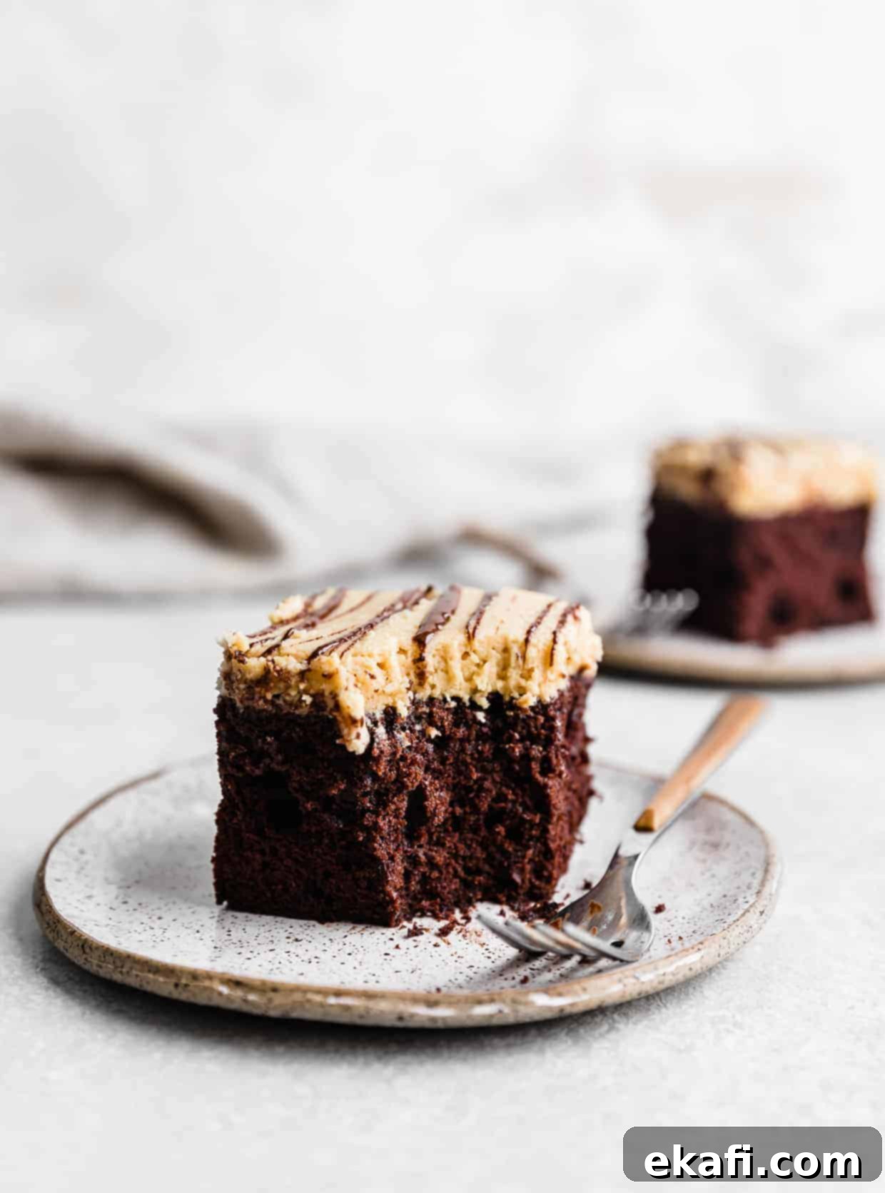 Chocolate Peanut Butter Symphony 14 A perfect slice of moist chocolate cake crowned with fluffy peanut butter frosting, presented on a simple white plate, inviting a delicious bite.