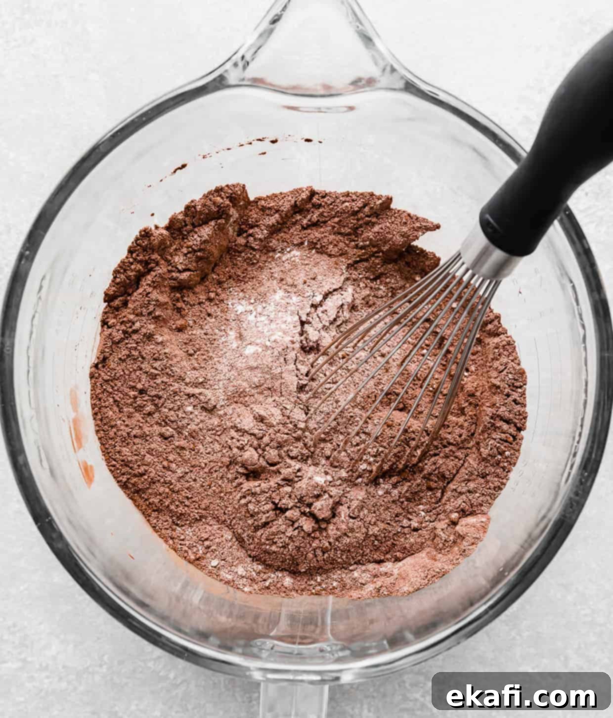 Chocolate Peanut Butter Symphony 4 Dry ingredients for making chocolate cake in a glass stand mixer bowl, with a whisk stirring everything, illustrating step 1 of the recipe.