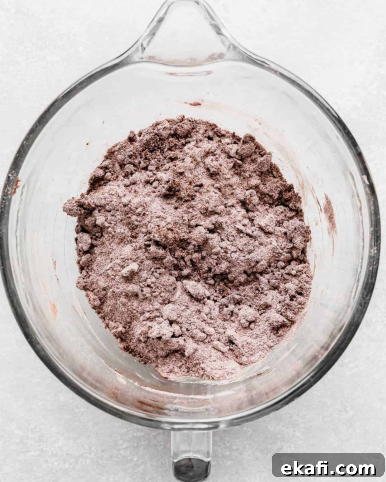 Chocolate Peanut Butter Symphony 5 A gray-brown colored dry ingredient mix in a glass bowl with chunks of butter distributed throughout, showing the sandy texture after adding fats.