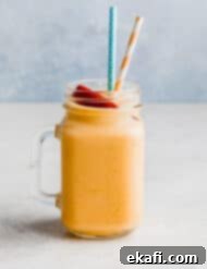 Creamy Peach Banana Bliss 9 A glass cup filled with a banana peach smoothie mixture and two straws.