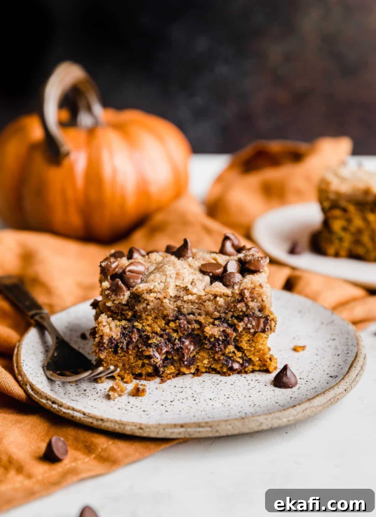 Cozy Pumpkin Chocolate Chip Coffee Cake 2 Pumpkin Chocolate Chip Coffee Cake on a white plate against a brown background.