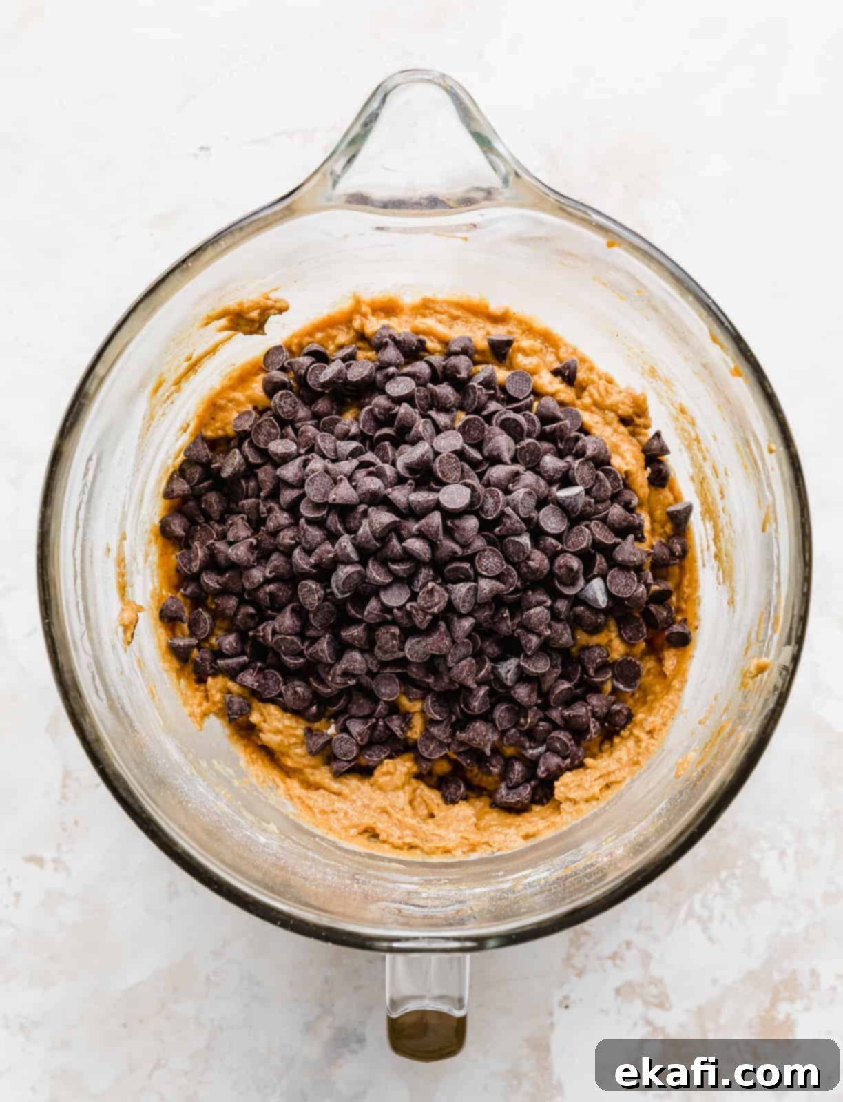 Cozy Pumpkin Chocolate Chip Coffee Cake 12 Chocolate chips in a glass bowl atop an orange cake batter mixture.