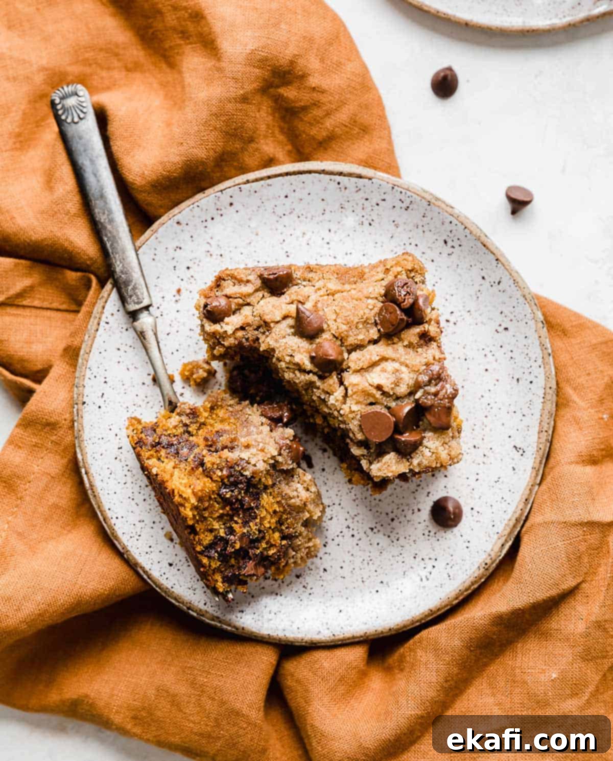 Cozy Pumpkin Chocolate Chip Coffee Cake 18 A slice of Pumpkin Chocolate Chip Coffee Cake on a white plate on a burnt orange napkin.