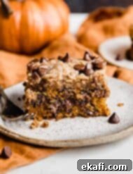 Cozy Pumpkin Chocolate Chip Coffee Cake 19 A slice of pumpkin chocolate chip coffee cake on a plate with an orange pumpkin in the background.