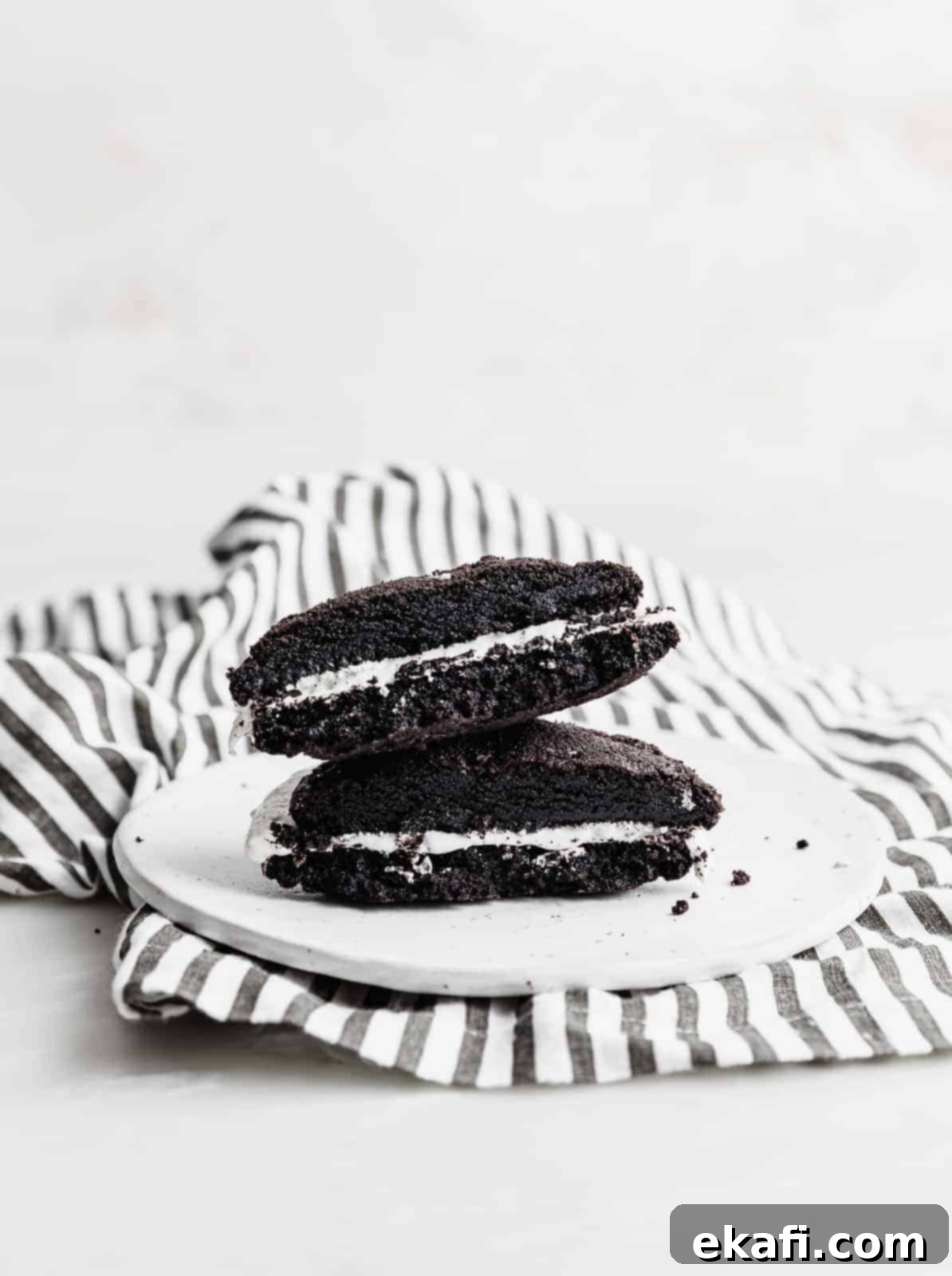 Crumbl Oreo Cookie Sandwiches 7 A giant homemade Oreo cookie sandwich cut in half, on a white plate.