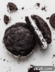 Crumbl Oreo Cookie Sandwiches 9 A copycat Crumbl Oreo cookie sandwich on a white background with Oreo crumbs surrounding the cookie.
