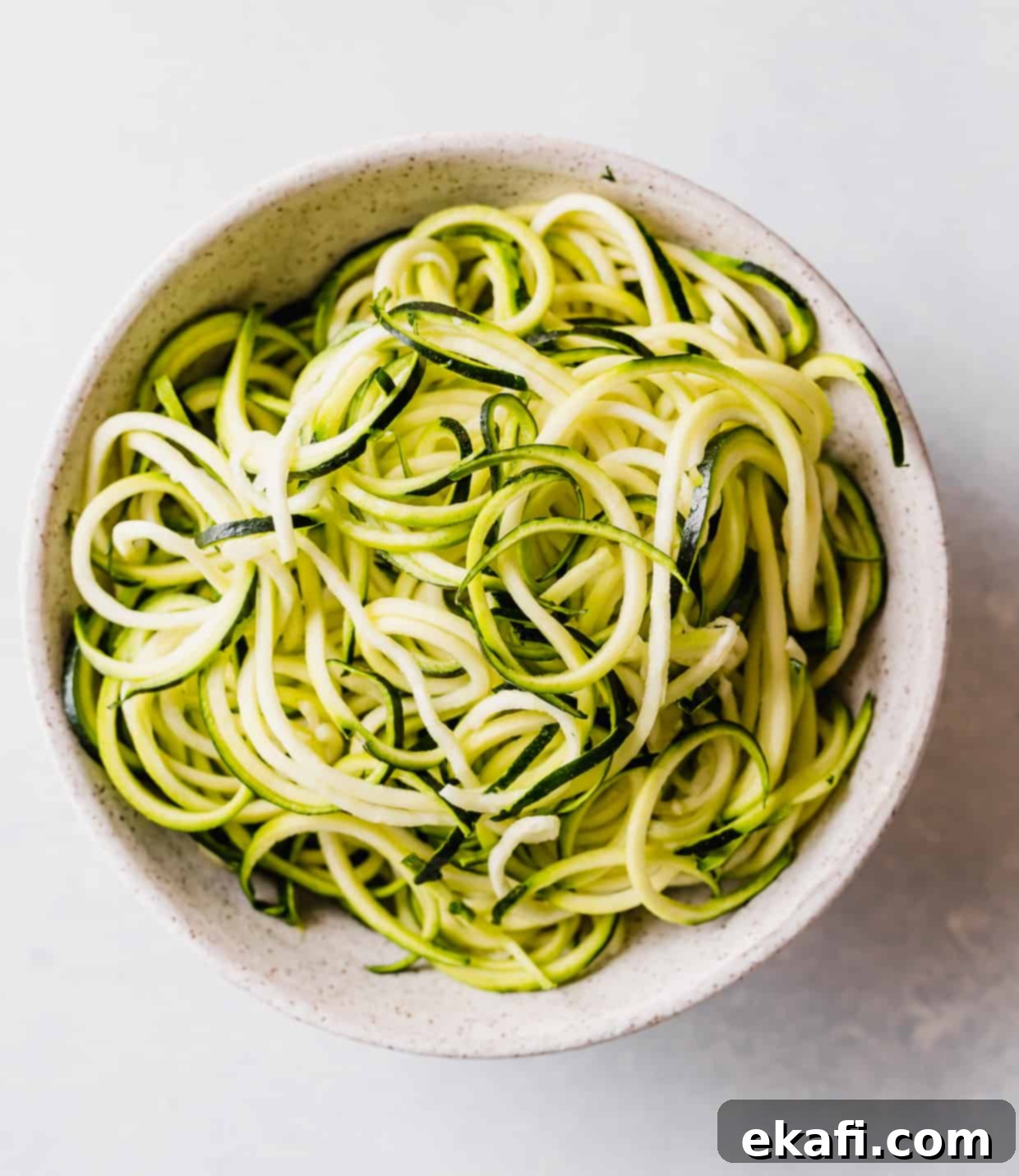Fluted Zucchetti 4 A generous pile of fresh zucchini noodles, ready to be sauced, in a white bowl.