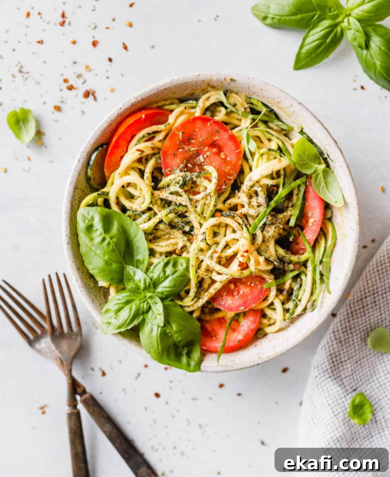 Fluted Zucchetti 7 Zucchini noodles used to create a vibrant 5-Minute Cheesy Zucchetti Bowl, beautifully garnished with bright red tomatoes, fresh basil, and Italian seasoning.
