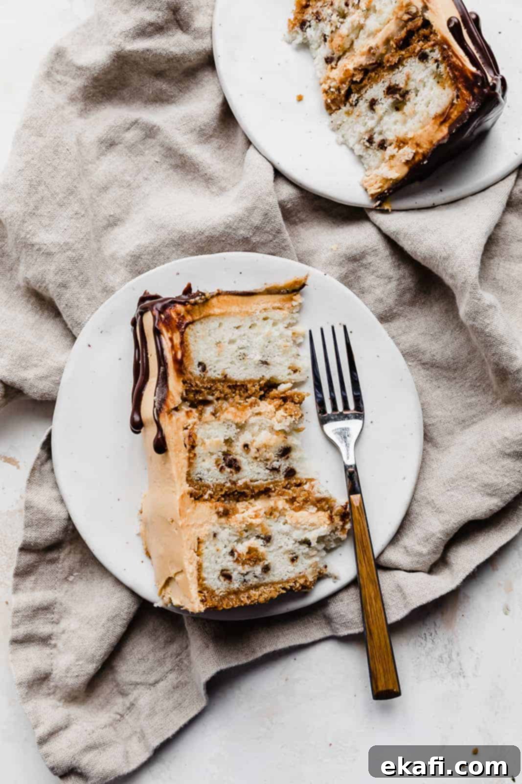 Seven-Layer Cake Bars 3 A perfect slice of 7 Layer Bar Cake on a pristine white plate, with a fork poised next to it, highlighting the distinct layers of graham cracker crust, coconut cake, coconut pecan filling, and butterscotch buttercream.