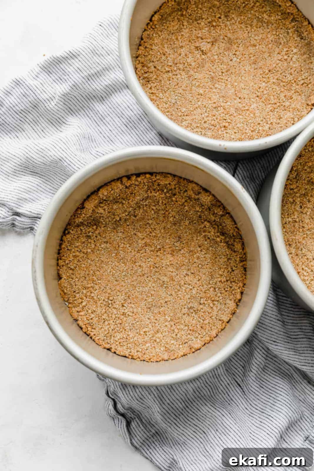 Seven-Layer Cake Bars 4 A golden-brown graham cracker crust perfectly pressed into a 6-inch round cake pan, ready for the cake batter.