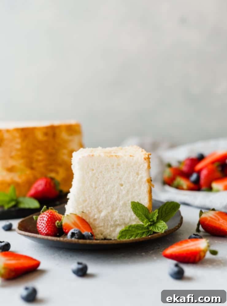 Συνταγή για Κέικ των Αγγέλων 14 Μια φέτα κέικ Angel Food σε μαύρο πιάτο, με φράουλες και μύρτιλα διασκορπισμένα στη σκηνή.