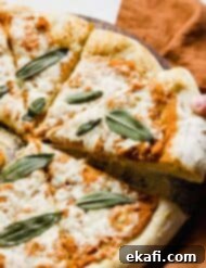 Harvest Moon Pizza 11 A small hand holding up a slice of golden Pumpkin Pizza topped with crispy sage.