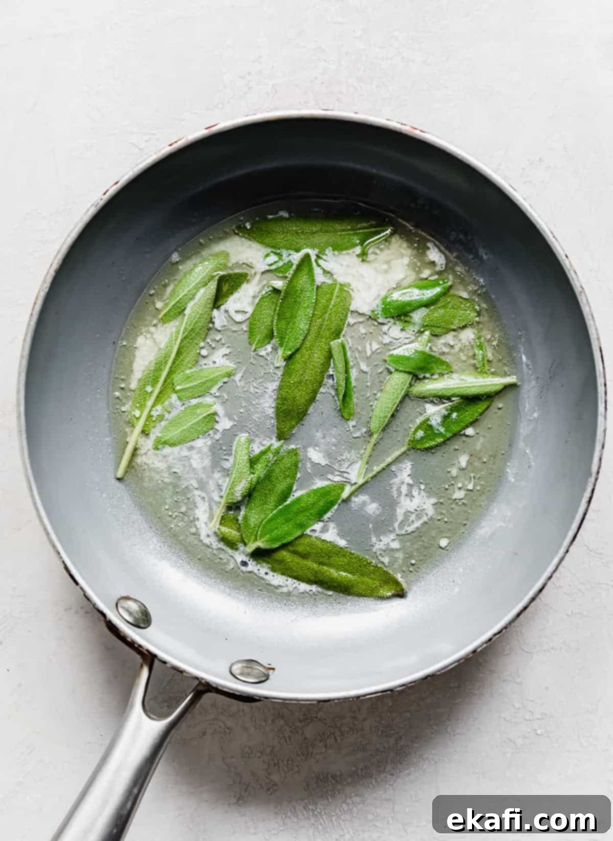 Harvest Moon Pizza 4 A gray skillet with melted butter and fresh sage leaves gently frying until crispy, ready for garnish.
