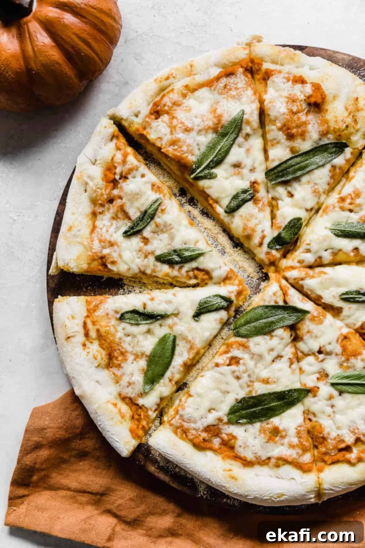 Harvest Moon Pizza 10 A full, freshly baked Pumpkin Pizza, golden-crusted and topped with crispy sage, on a gray background, ready to be sliced.