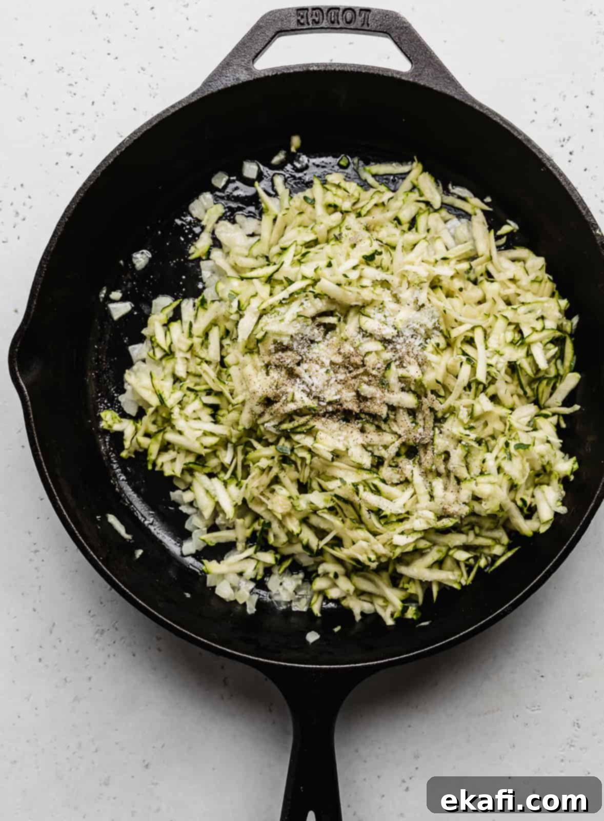 Summer Zucchini Delight 4 A black skillet with shredded zucchini in it.