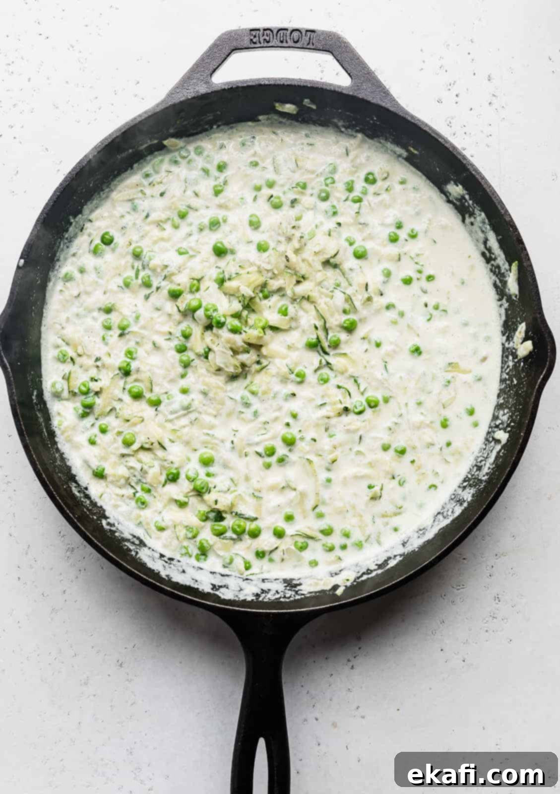 Summer Zucchini Delight 9 A black skillet with shredded zucchini in a white sauce.