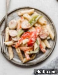 Spicy Cajun Sausage Pasta 12 A delicious plate of Cajun Sausage Pasta, featuring sliced green and red bell peppers, all coated in a rich, creamy sauce, served on a gray plate.