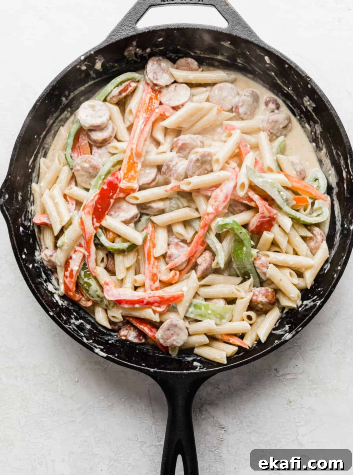 Spicy Cajun Sausage Pasta 9 A black skillet filled with the finished creamy Cajun Sausage Pasta, showcasing the perfectly coated pasta, colorful peppers, and savory sausage, all ready to be served.